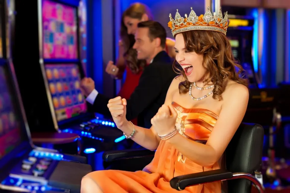 vrouw in oranje Koningsdag-outfit zit juichend achter gokkast in casino