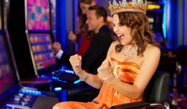 vrouw in oranje Koningsdag-outfit zit juichend achter gokkast in casino
