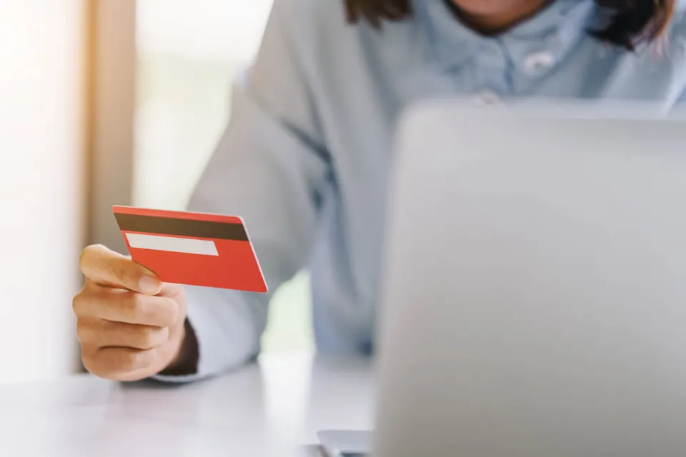 vrouw voor laptop houdt bankpas vast om online te betalen