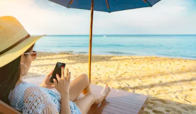 vrouw met telefoon op strand onder parasol