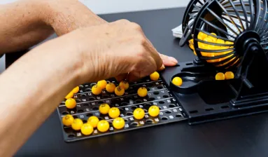 twee handen bij bingo molen met gele balletjes