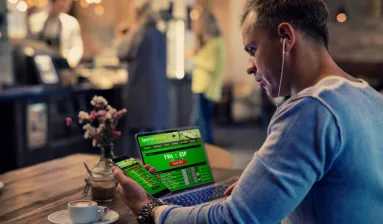 man kijkt naar sportsbook op laptop en telefoon